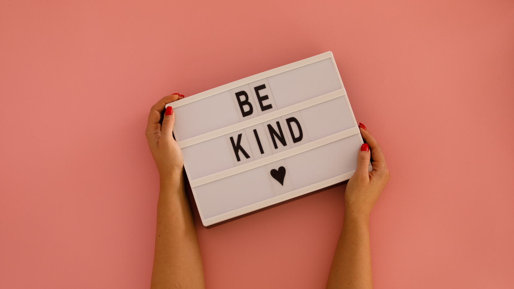 person holding a letter board with the words be kind on it